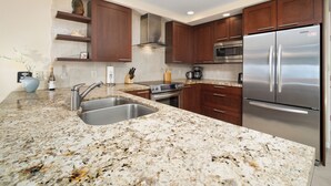 A modern kitchen with granite countertops, stainless steel appliances, and wooden cabinets.
