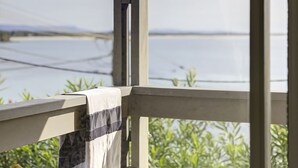 Barandilla de madera con vista a un cuerpo de agua y vegetación.