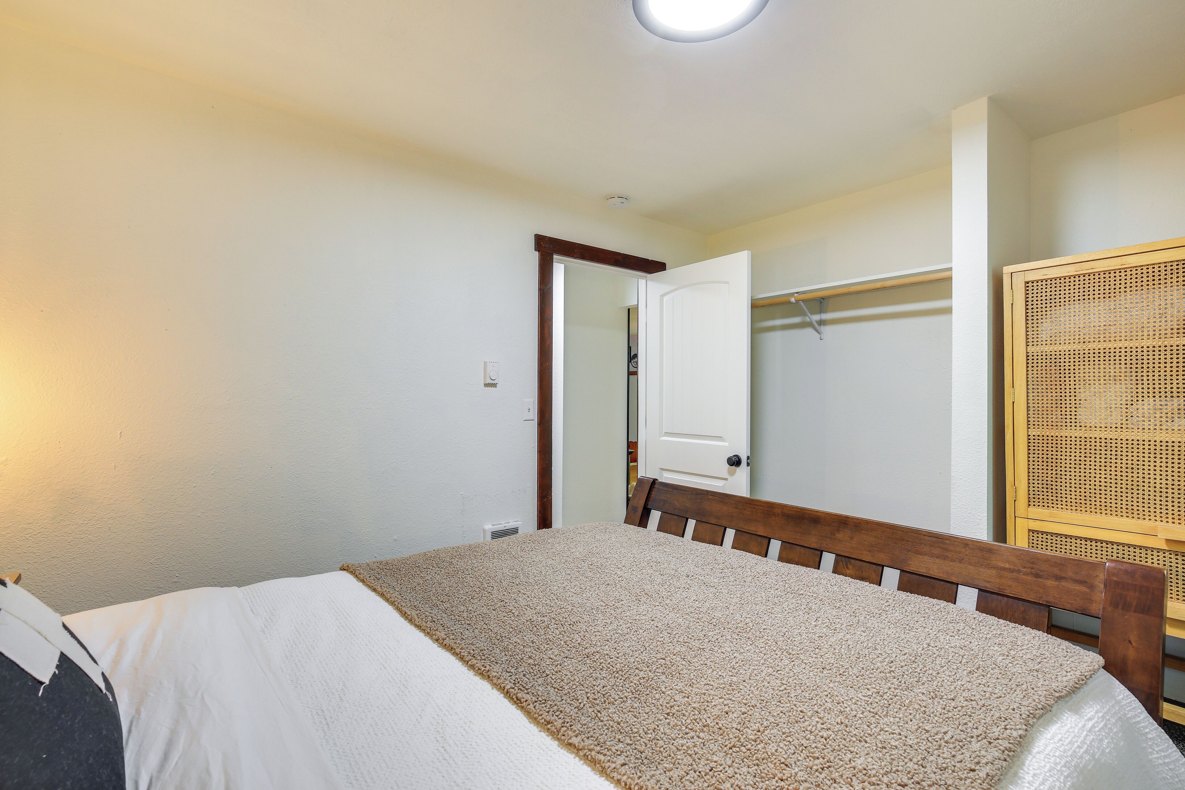 A bedroom with a bed, a wooden headboard, a closet with a door, and a woven basket.