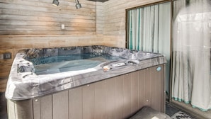 Un jacuzzi en una habitación de madera con un banco, una ventana con cortinas y una puerta.