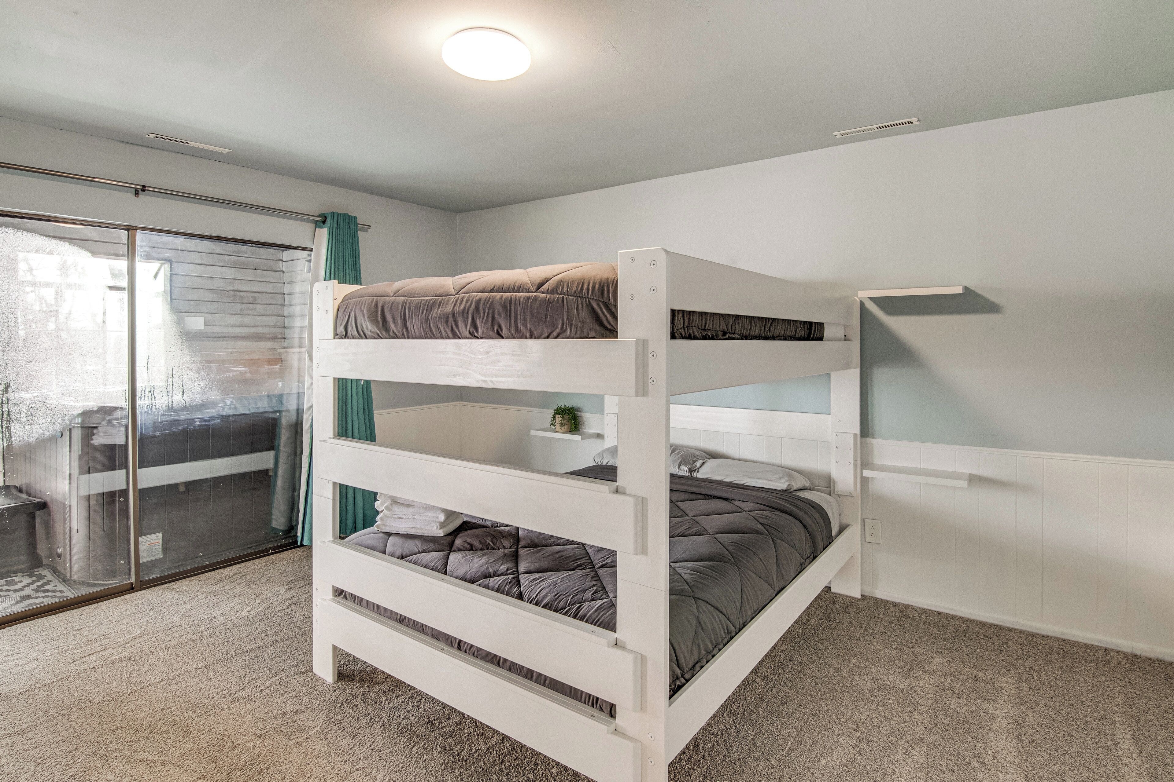A bunk bed room with a sliding glass door leading to a balcony, white walls, and a ceiling light.