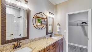 Un bagno con un lavabo doppio, un ampio specchio e uno spazio doccia.