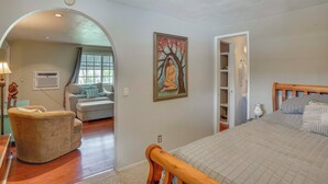 A bedroom with a wooden bed, a sofa, a chair, and a painting on the wall. - Pet-friendly Studio in Costa Mesa - 7 Mi to Beach! (Costa Mesa)