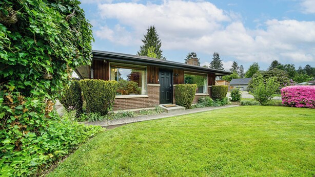 A modern house with a well-maintained lawn, a wooden front door, and a brick facade. - 1 Mi to Snoqualmie River: Pet-friendly Getaway (Carnation)