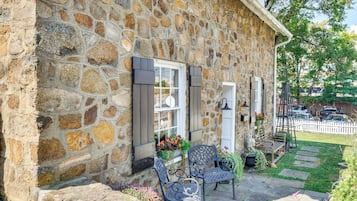 Un bâtiment en pierre doté d’une fenêtre et d’une porte, d’un banc et d’un petit espace aménagé en jardin.