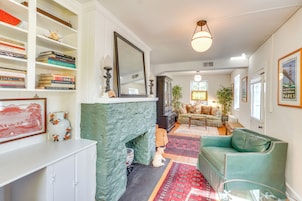 Una sala de estar con chimenea, un sofá verde y una estantería llena de libros.