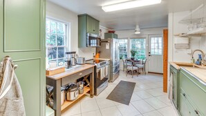 A modern kitchen with green cabinets, stainless steel appliances, and a wooden countertop. - Cottage w/ Furnished Patio & Garden: Dtwn Leesburg (Leesburg)