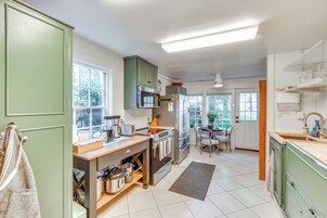Una cocina moderna con armarios verdes, electrodomésticos de acero inoxidable y encimera de madera.