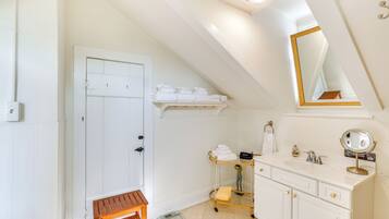 A bathroom with a white vanity, a mirror, a towel rack, and a bench.