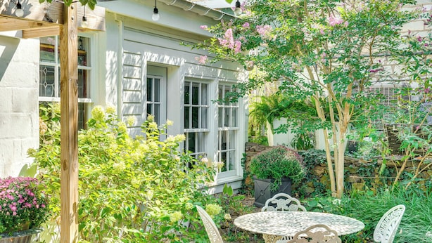 A garden with a wooden pergola, a table with chairs, and a variety of plants and flowers. - Cottage w/ Furnished Patio & Garden: Dtwn Leesburg (Leesburg)