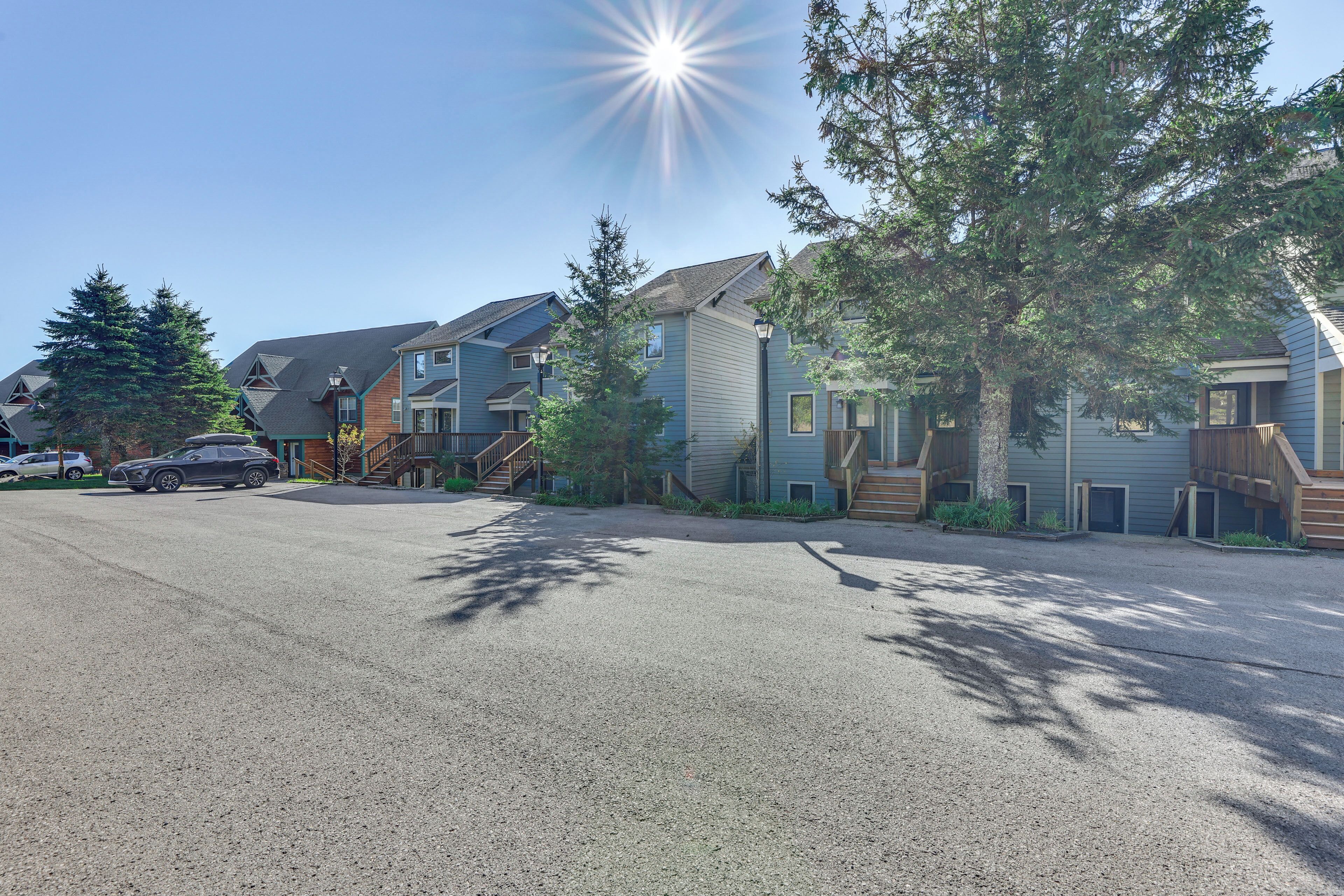 A residential street with houses, a driveway, and a parked car.