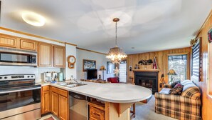 A kitchen with wooden cabinets, a large island, stainless steel appliances, and a fireplace. - Located in Snowshoe Resort: Townhome w/ Deck! (Snowshoe)