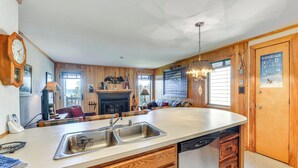 A kitchen with a central island, wooden cabinetry, a built-in dishwasher, and a large window providing natural light. - Located in Snowshoe Resort: Townhome w/ Deck! (Snowshoe)