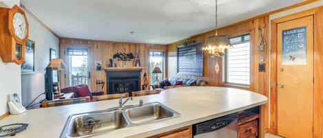 A kitchen with a central island, wooden cabinetry, a built-in dishwasher, and a large window providing natural light.