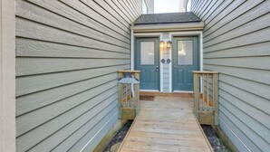 A narrow wooden pathway leading to a door with two lights above it. - Located in Snowshoe Resort: Townhome w/ Deck! (Snowshoe)