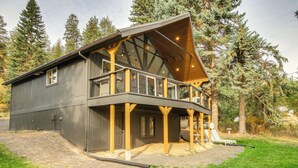 A modern two-story building with a balcony, large windows, and a wooden deck.