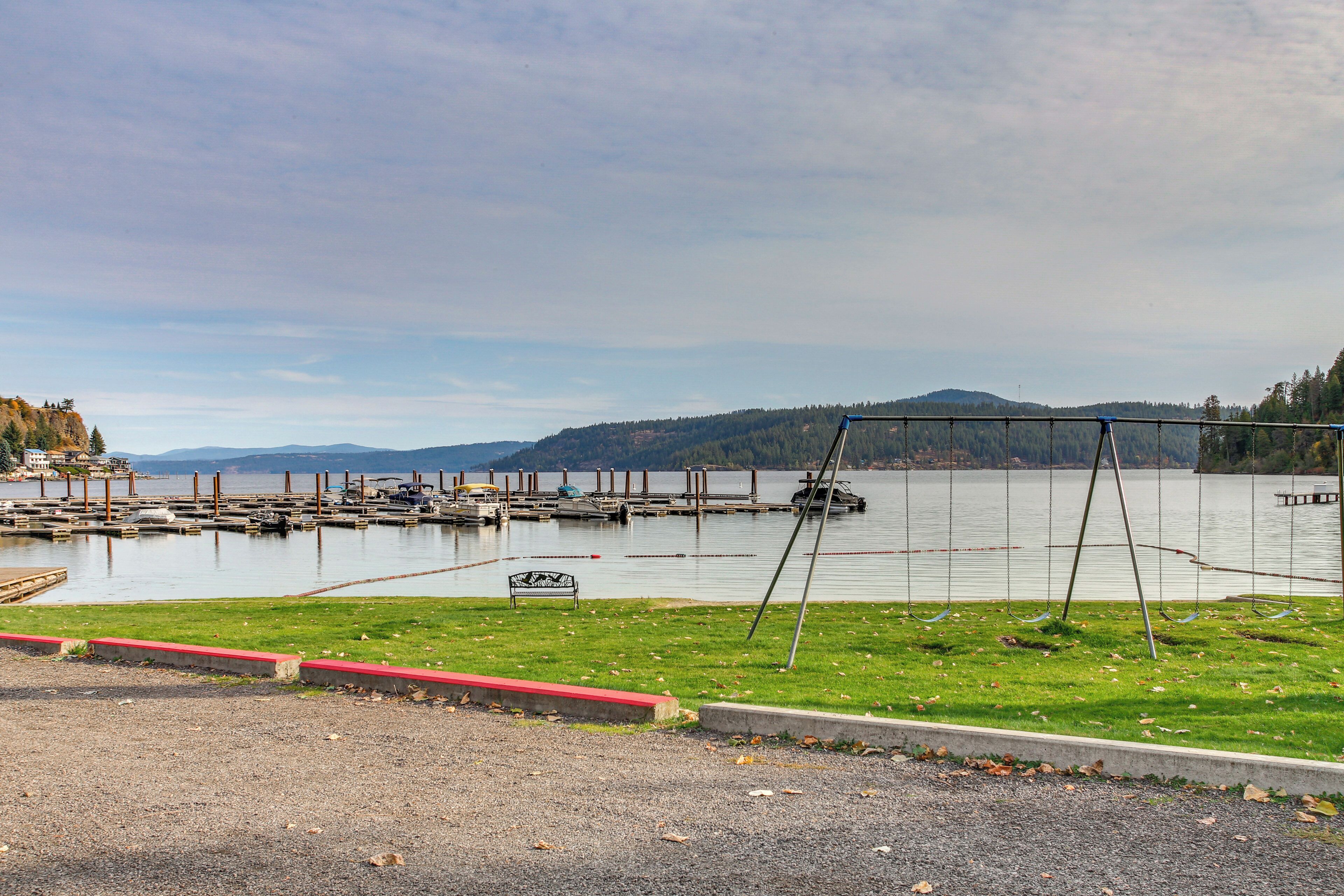 A marina with boats docked, a swing set, and a grassy area with a bench.