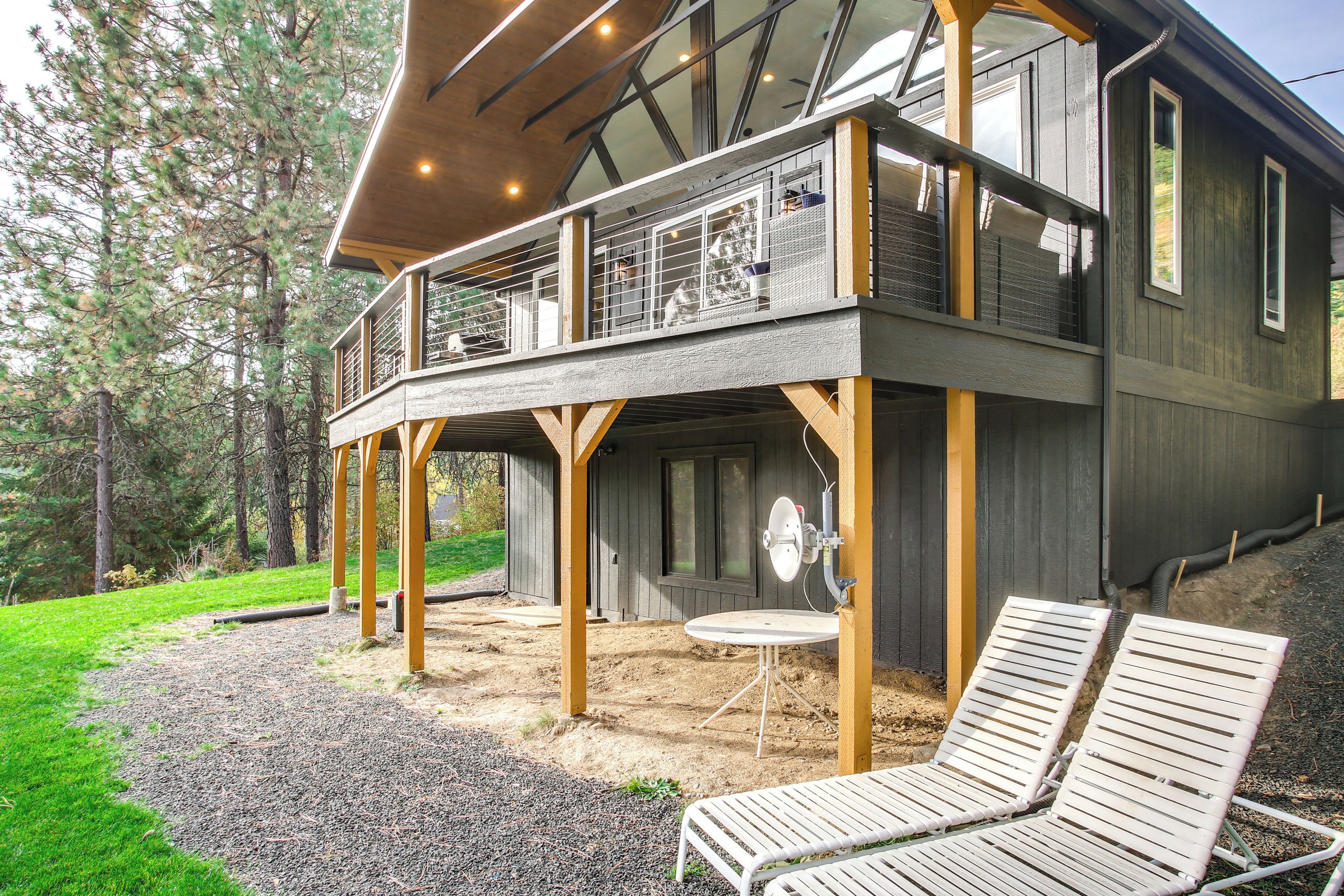 A two-story wooden house with a balcony, outdoor seating, and a satellite dish.