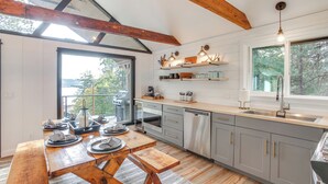 A modern kitchen with wooden beams, a large dining table, and a view of the outdoors.