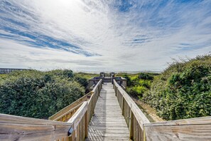 A wooden boardwalk leading to a beach area with a wooden structure at the end. - Home on Ocean Isle Beach w/ Catwalk & Deck (Ocean Isle Beach)