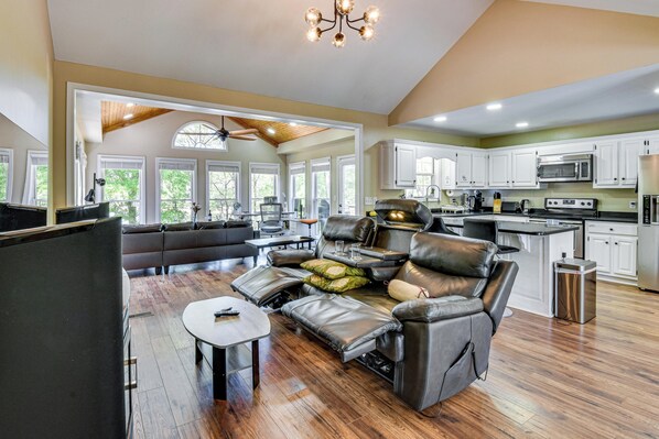 A spacious living area with a leather sofa, a dining table, and a kitchen in the background.