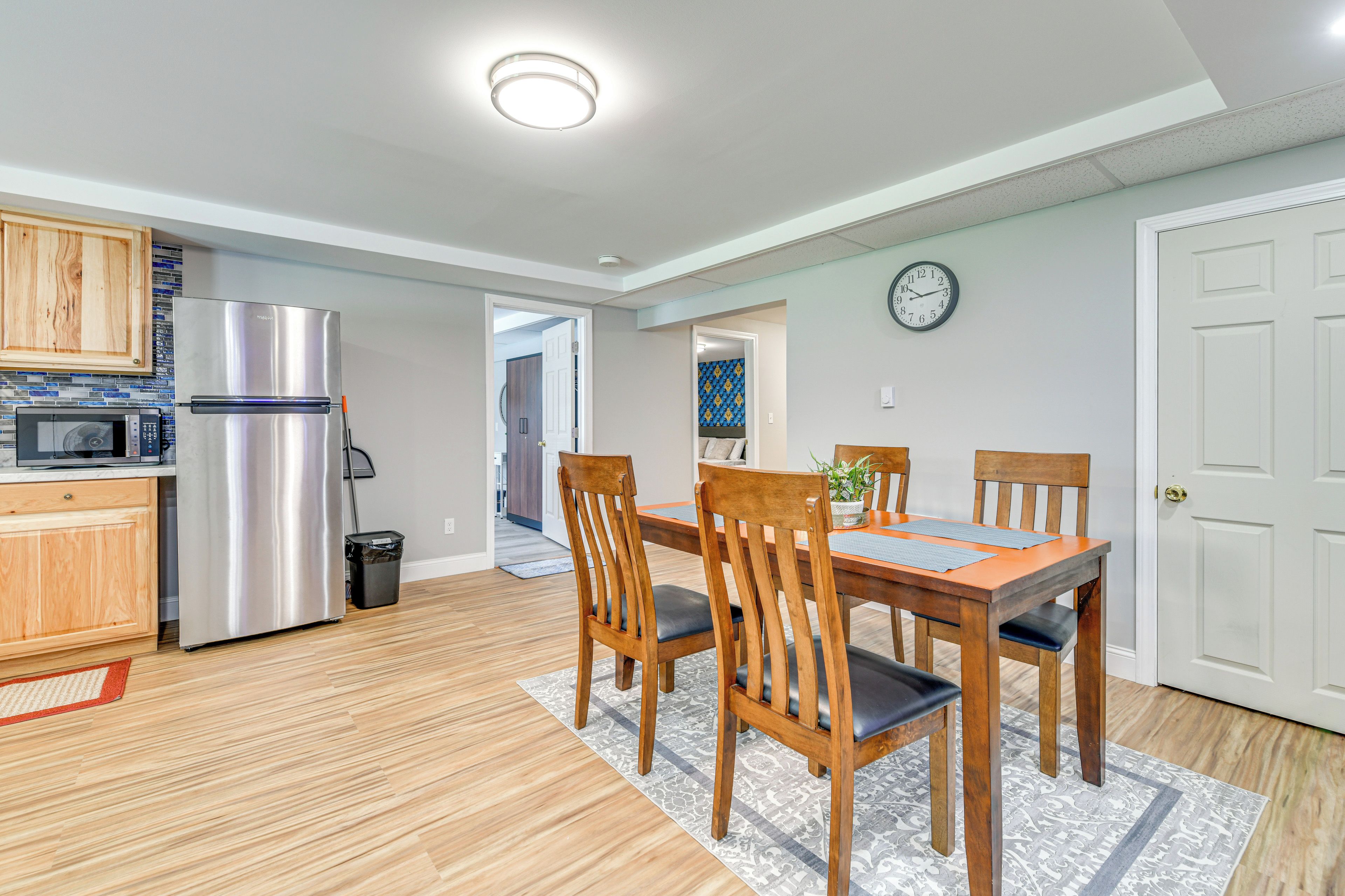 Een moderne keuken met roestvrijstalen apparatuur, houten kastjes en een eethoek met een tafel en stoelen.