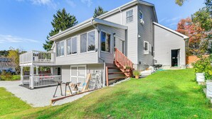 A two-story house with a covered porch, a staircase, and a garage. - Lake Champlain Fun: Apt w/ Fire Pit & Large Yard! (Essex Junction)
