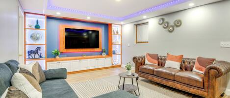 Una sala de estar moderna con un televisor de pantalla plana grande, un sofá de cuero y un sofá modular.