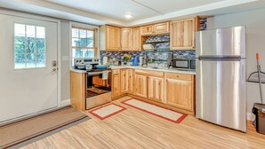 A modern kitchen with wooden cabinets, stainless steel appliances, and a tiled backsplash. - Lake Champlain Fun: Apt w/ Fire Pit & Large Yard! (Essex Junction)