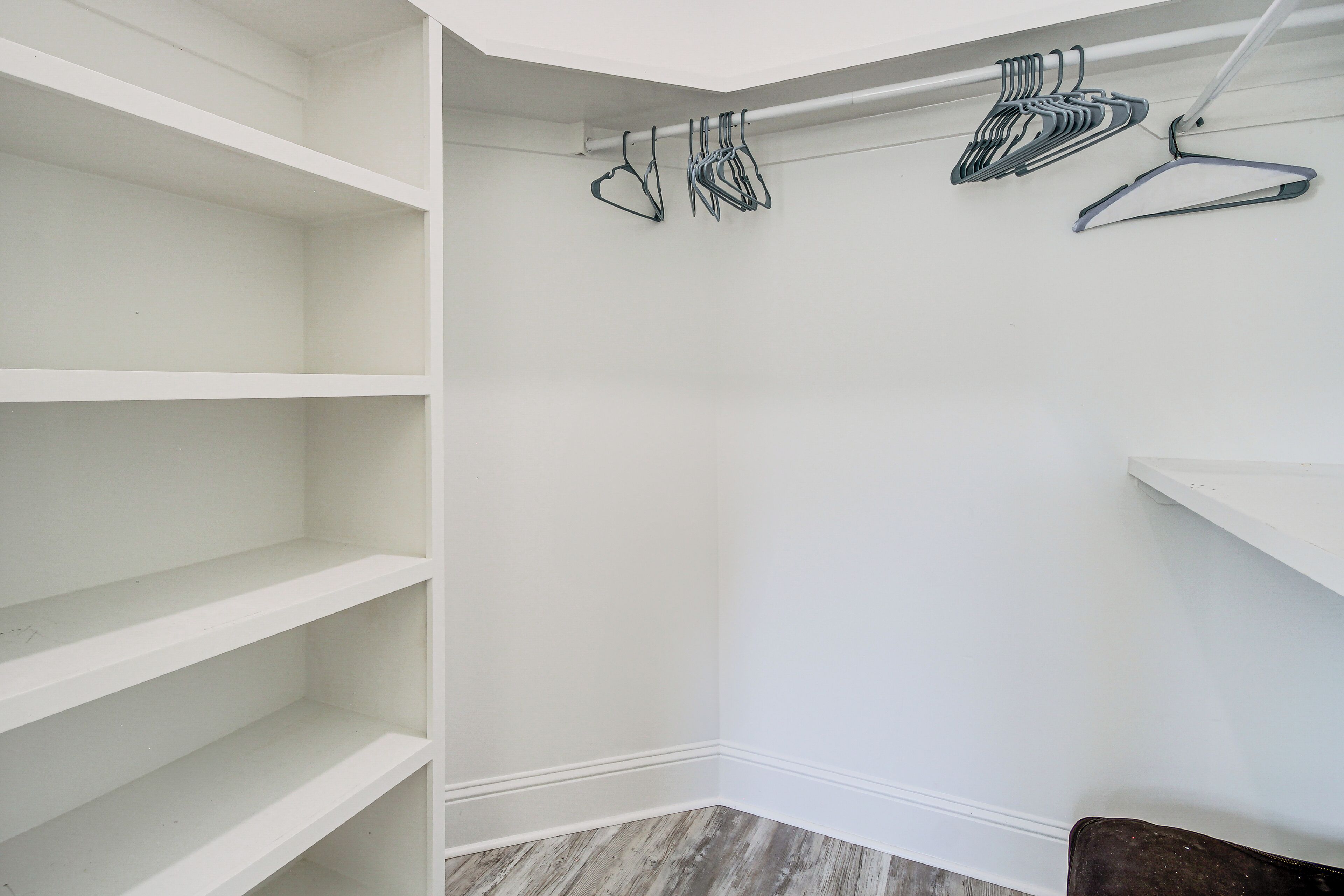 Ein weißer Kleiderschrank mit mehreren Einlegeböden und einer Kleiderstange.