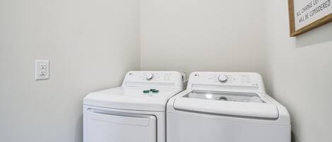A laundry room with two white front-loading washing machines and a sign on the wall.