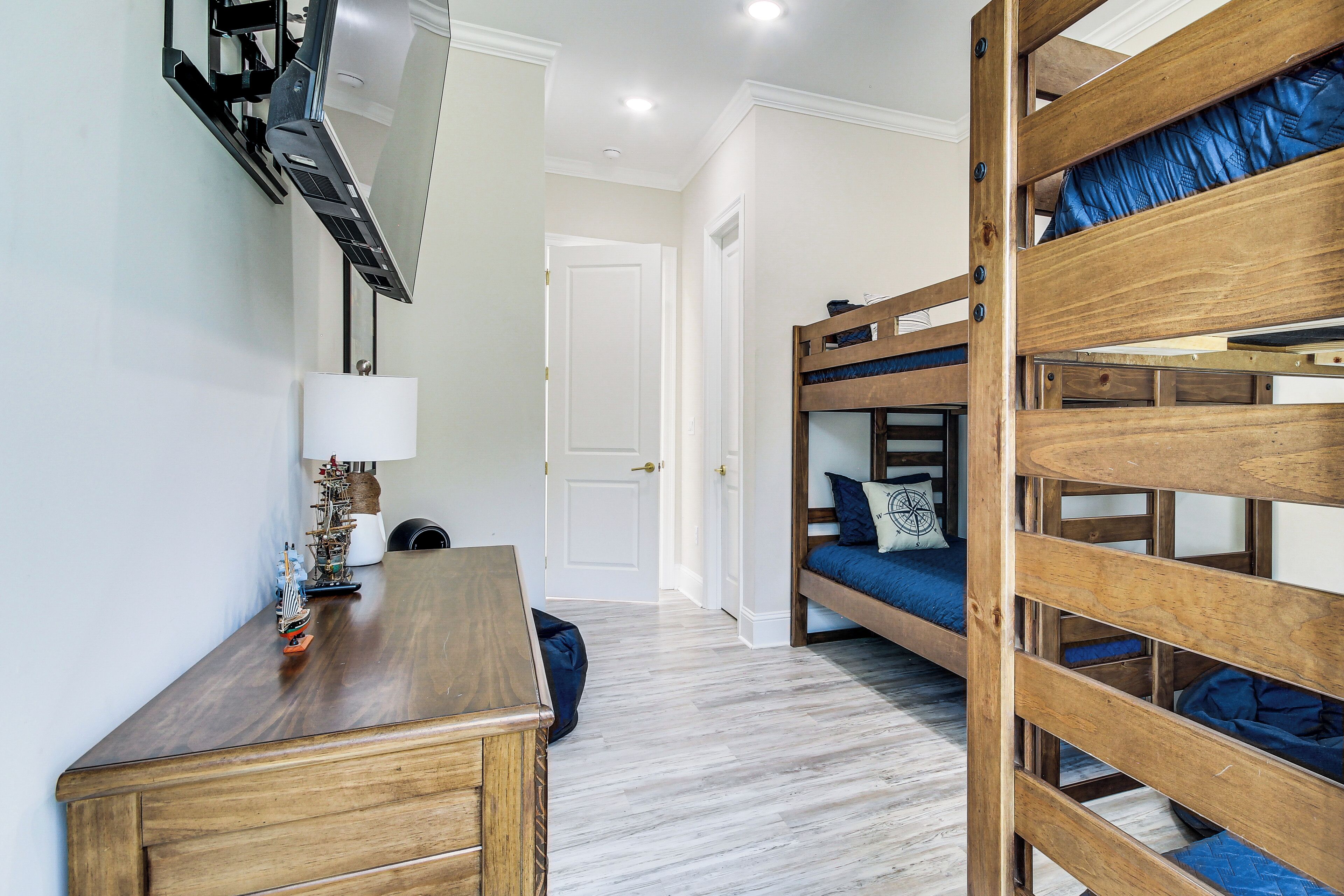 A room with bunk beds, a desk, a lamp, and a small plant.