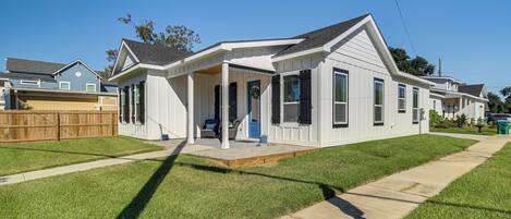 A single-story house with a covered porch, a front yard with a sidewalk, and a wooden fence.