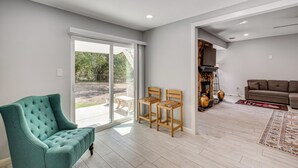 A spacious living area with a teal armchair, two wooden chairs, a brown sofa, and a large window offering a view of the outdoors. - ~ 1 Mi to Lavon Lake: Princeton Retreat (Princeton)