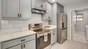 A modern kitchen with white cabinets, stainless steel appliances, and a marble countertop. - ~ 1 Mi to Lavon Lake: Princeton Retreat (Princeton)