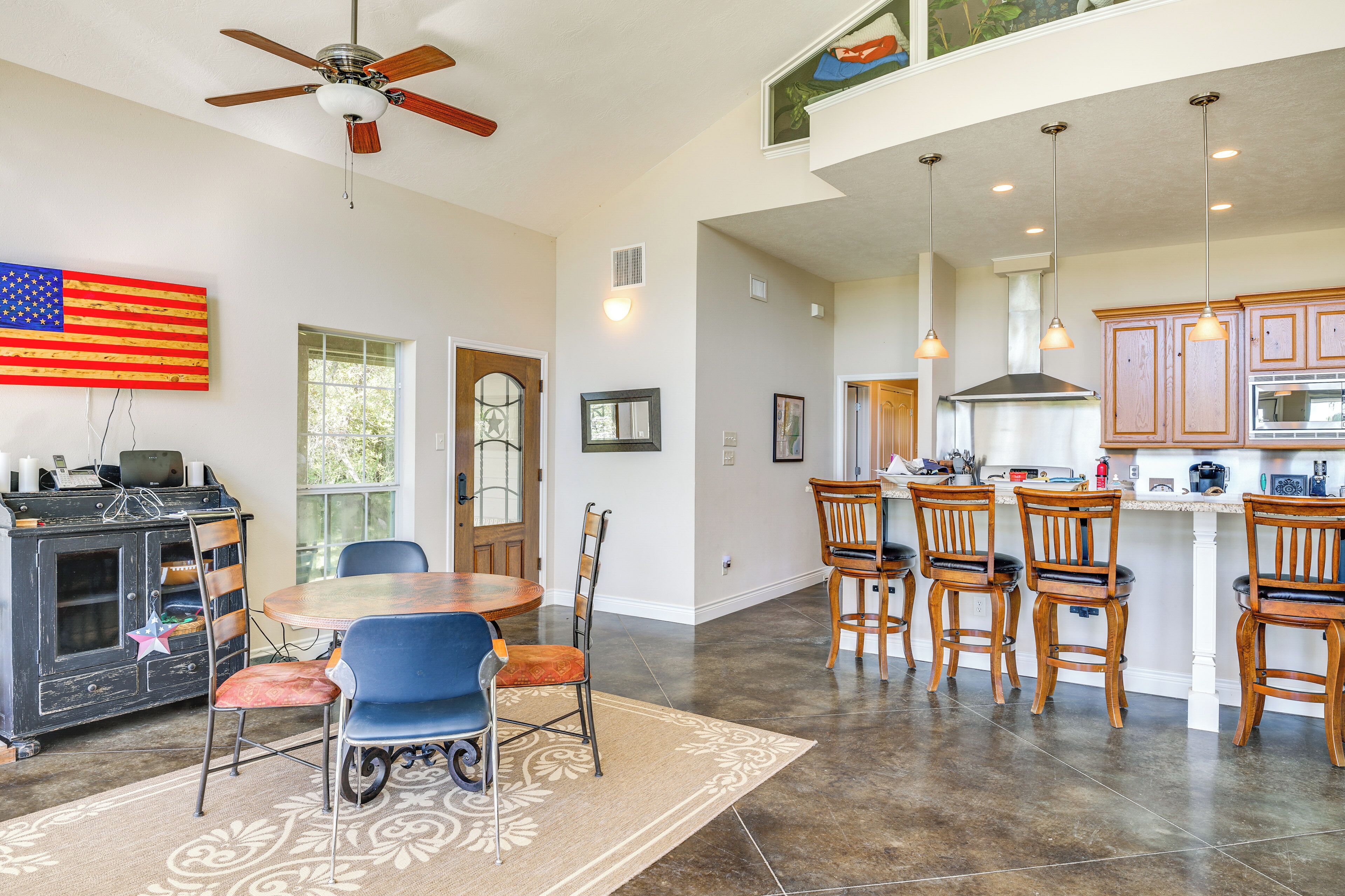 A spacious kitchen with a central island, wooden cabinets, and pendant lighting.