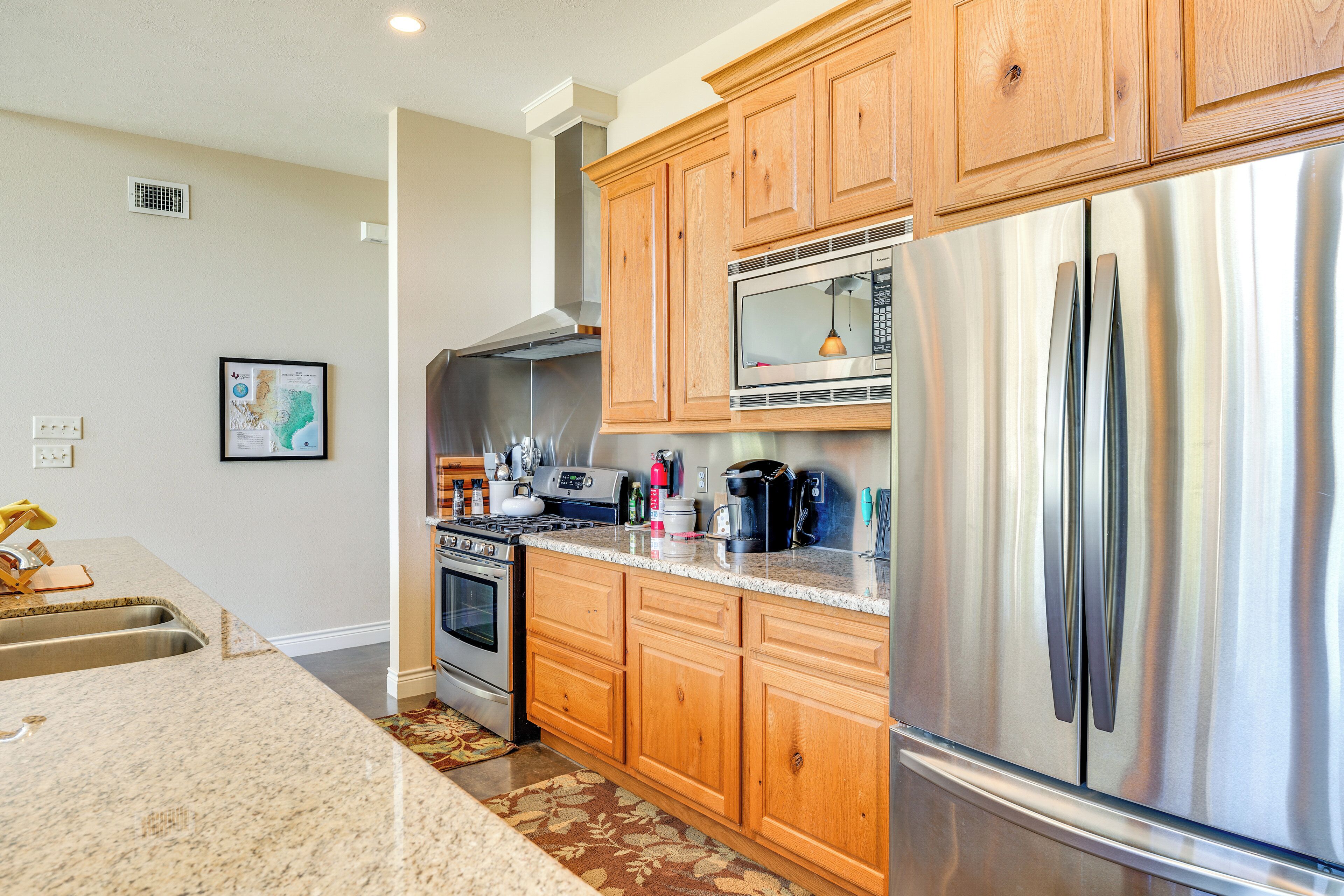 A modern kitchen with wooden cabinets, stainless steel appliances, and granite countertops.