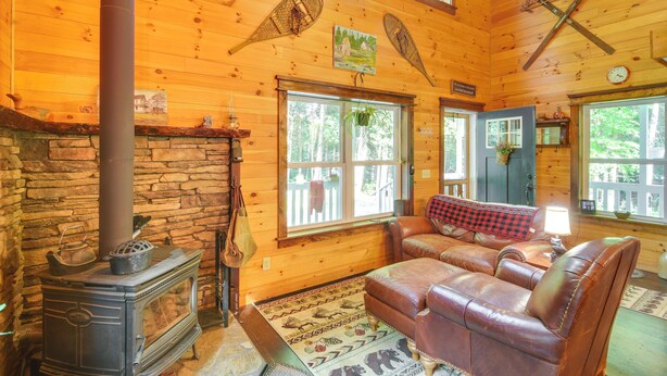 L’intérieur d’un chalet accueillant, avec une cheminée en pierre, un canapé en cuir et des murs en bois.