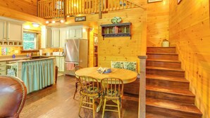 L’intérieur d’un chalet en bois comprend un coin repas, une cuisine et un escalier.