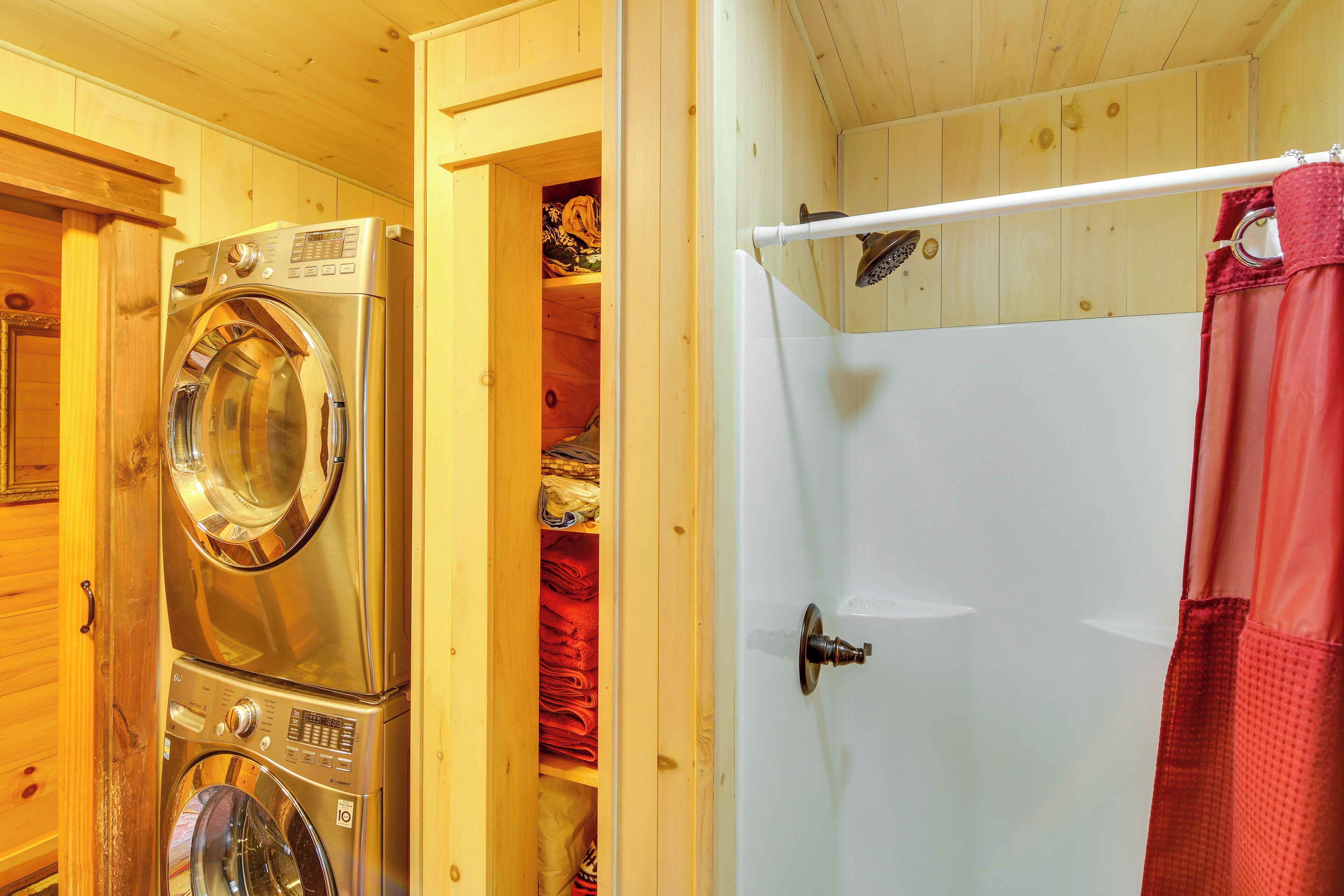 A laundry area with stacked washing machines and a white door leading to a room with a shower curtain.
