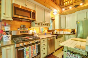 Una cocina con electrodomésticos de acero inoxidable, armarios de madera y una variedad de utensilios y aparatos de cocina.