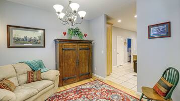 A living room with a beige sofa, a patterned rug, a wooden cabinet, and a green chair.