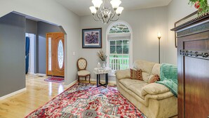 A spacious living room with a large window, a chandelier, a patterned rug, and a wooden cabinet. - Breaks Home: 3 Mi to ATV Trails! (Breaks)