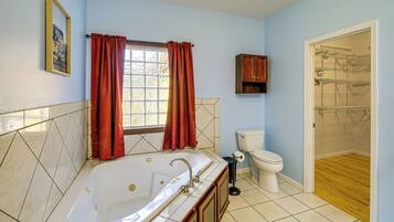 A bathroom with a bathtub, toilet, and shower area.