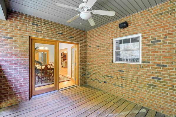 A room with a brick wall, wooden flooring, a ceiling fan, and a sliding glass door leading to another room. - Breaks Home: 3 Mi to ATV Trails! (Breaks)