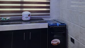 Una cocina moderna con una lámpara de techo original, horno empotrado y ventana con persianas horizontales.