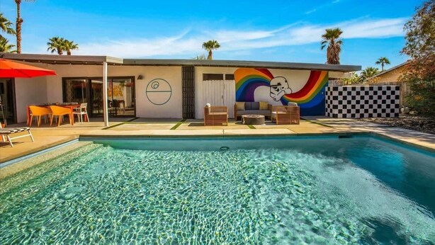 A modern house with a swimming pool, a mural, and outdoor furniture.