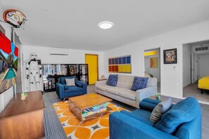 A modern living room with a sofa, coffee table, and a bookshelf.
