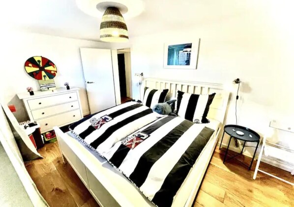 A bedroom with a bed, a dresser, a chair, and a lamp.