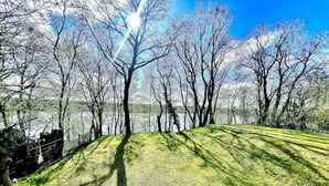 A park with a grassy area, trees, and a body of water in the background.